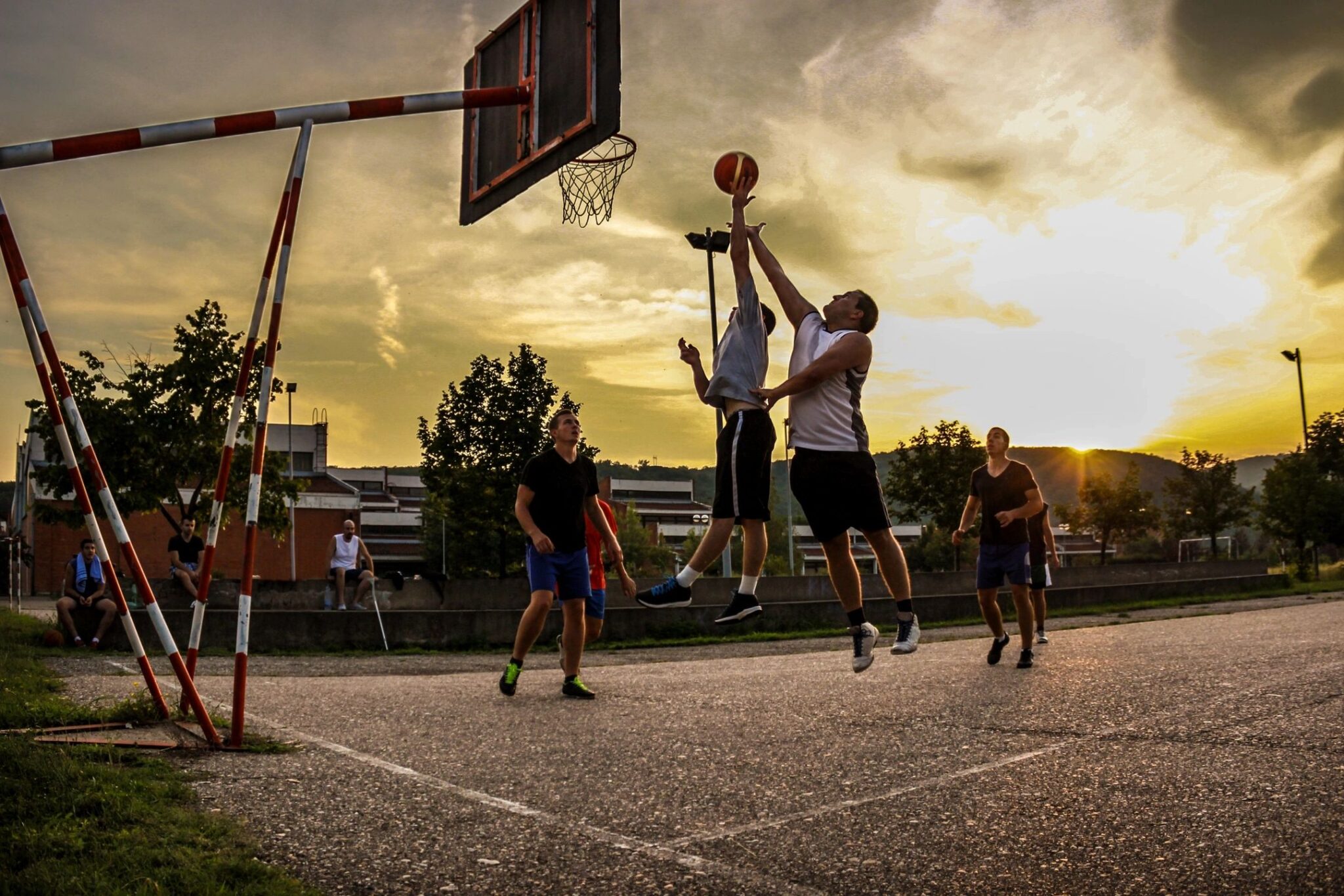 A group of people playing basketball on an asphalt court.