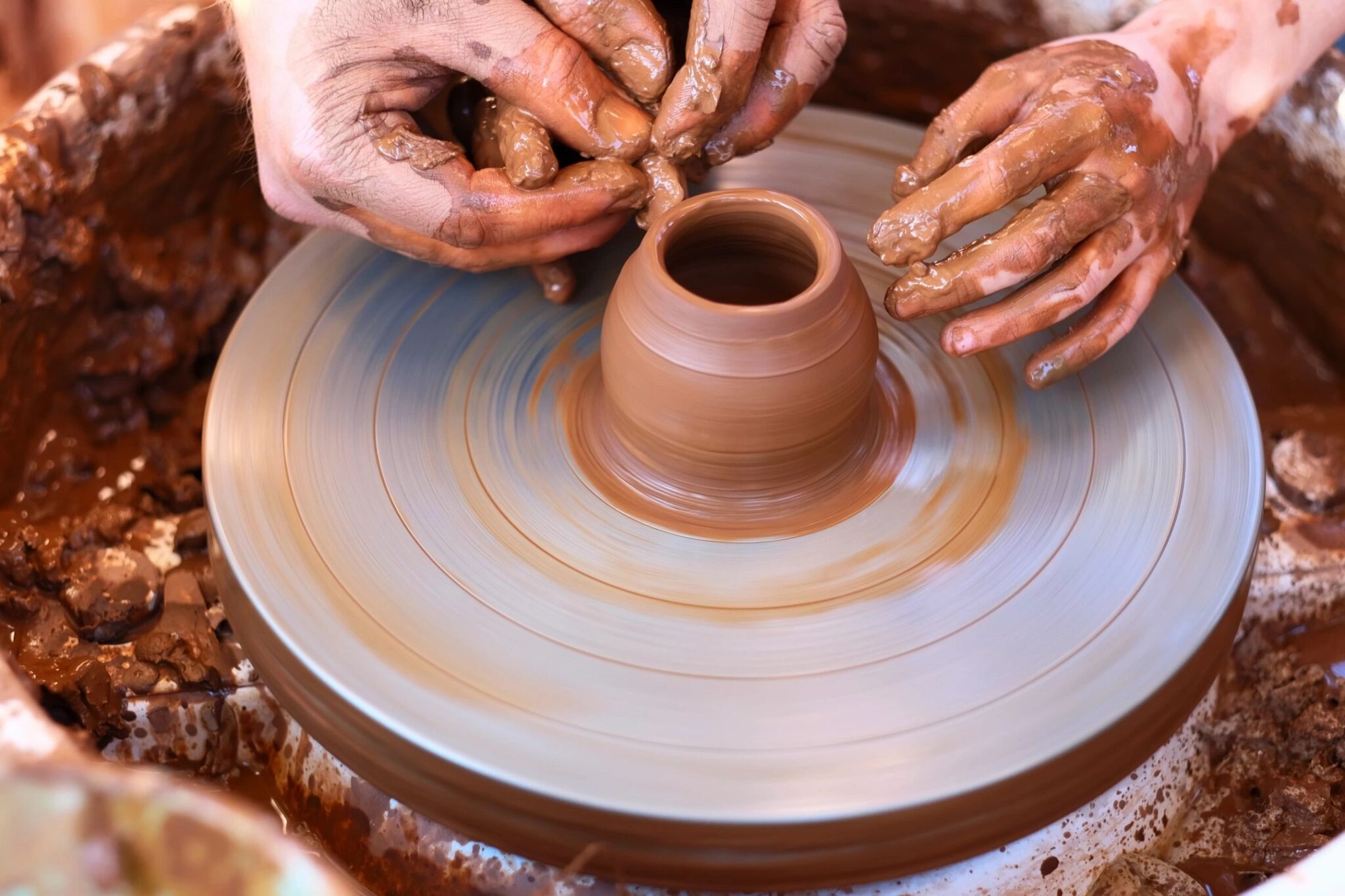 A person is making pottery on the potter 's wheel.