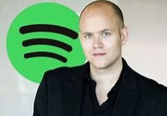 A man standing in front of a green spotify logo.