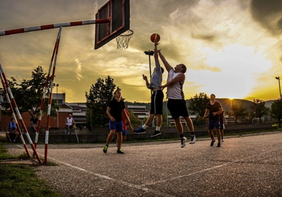 A group of people playing basketball on an asphalt court.